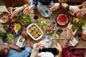 Friends sharing a colorful, fresh meal around a wooden table.